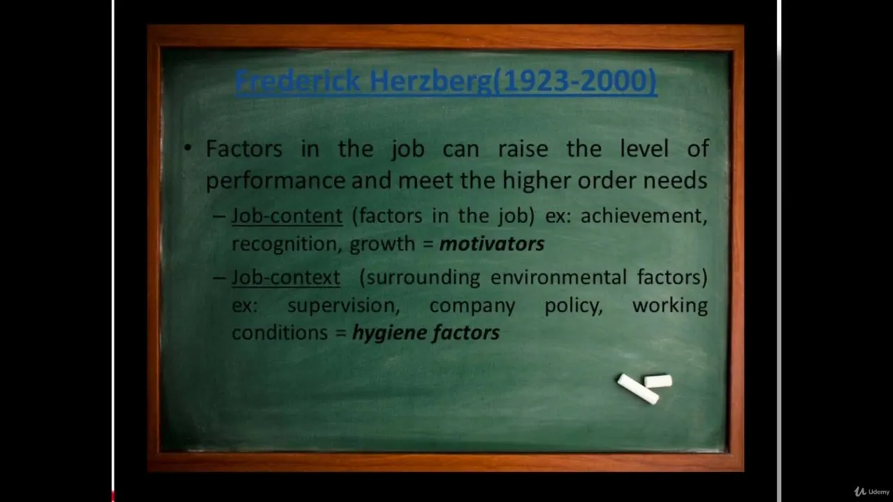 A green chalkboard with a wooden frame displays a slide about Frederick Herzberg, listing job-content and job-context factors.